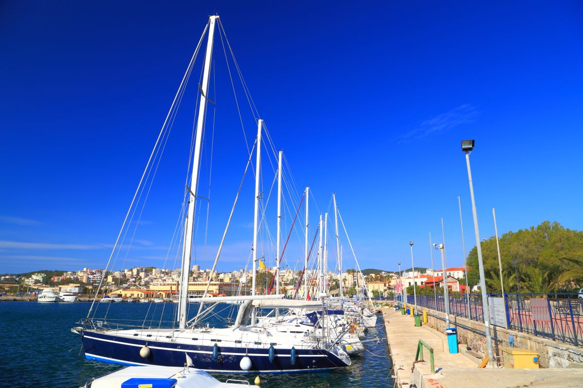 Sunny pier with sail boats at anchor in Lavrion harbor, Attica, Greece